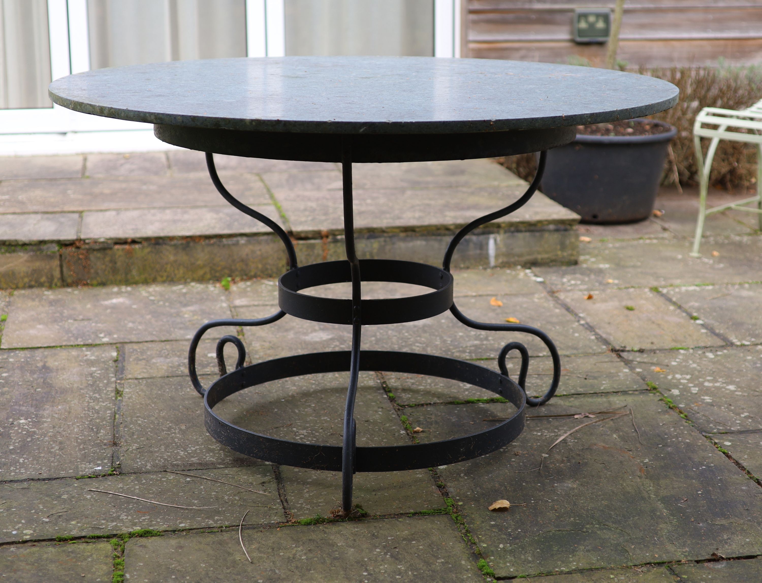 A wrought iron garden table with circular green marble top, width 123cm height 75cm